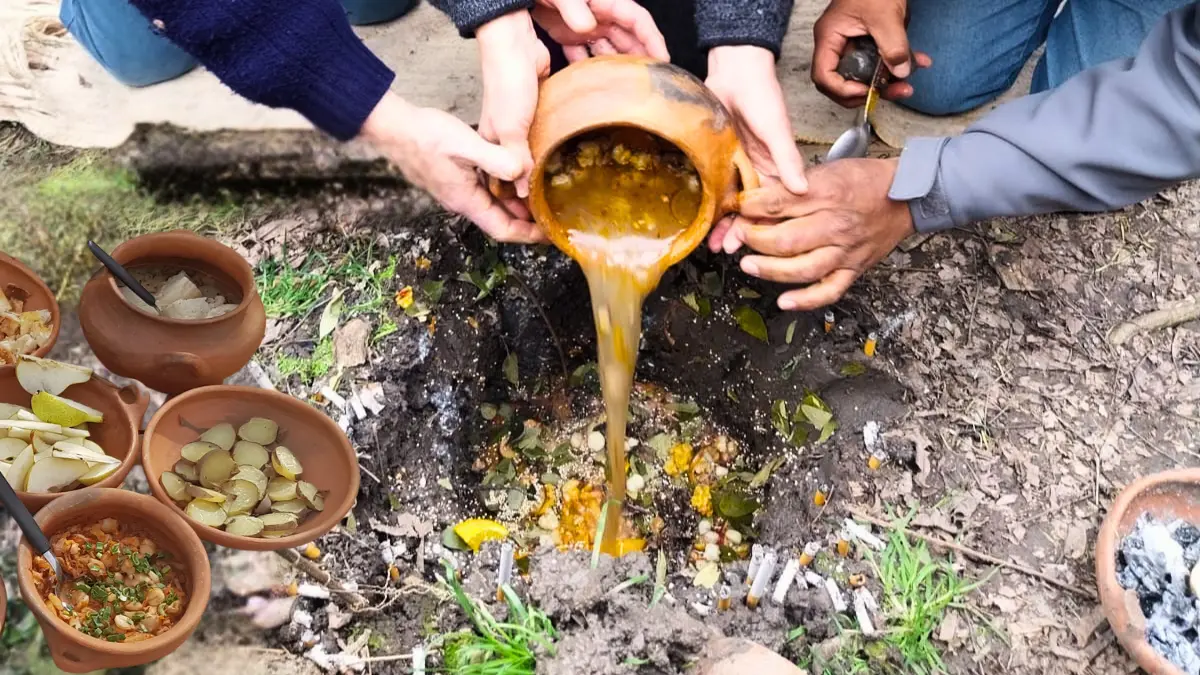 Jujeños ofreciendo comida a la Pachamama en la corpachada con el paisaje del Hornocal de fondo en Jujuy